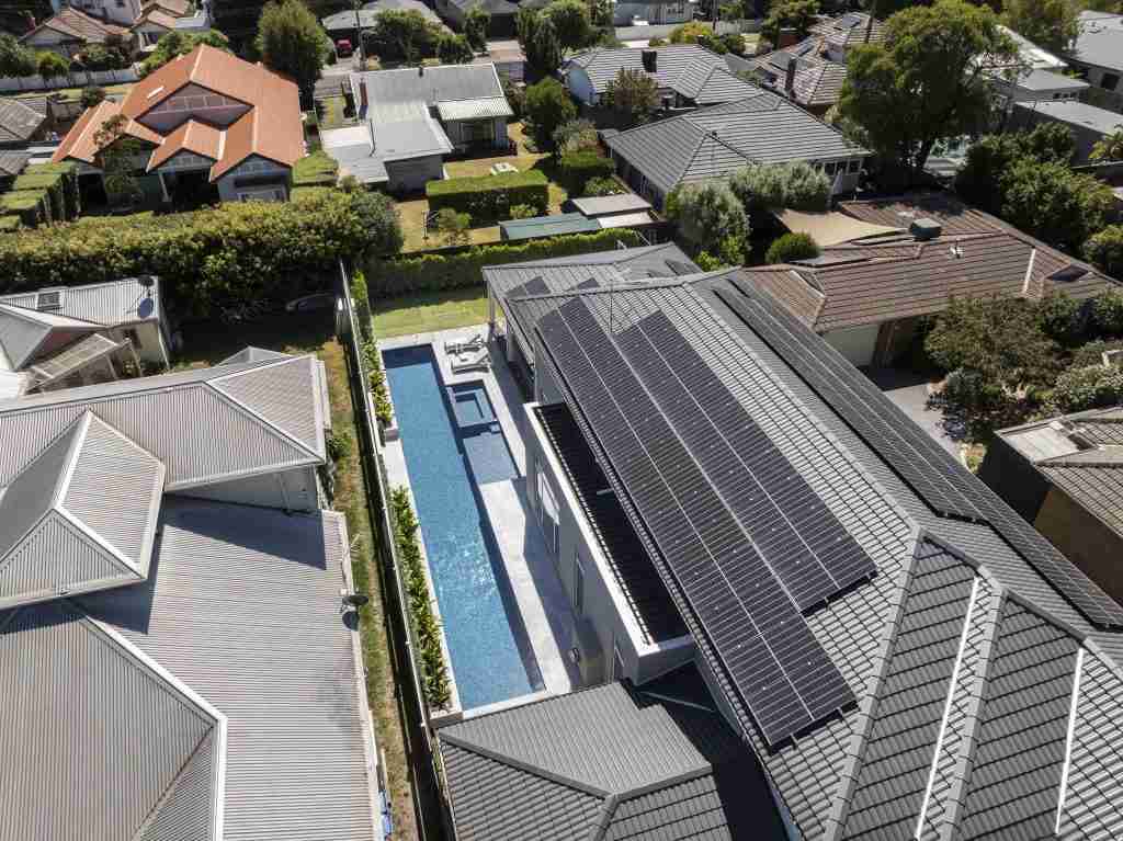 Beautiful blue 20-metre lap pool shot from above, running alongside a double storey home in Hampton